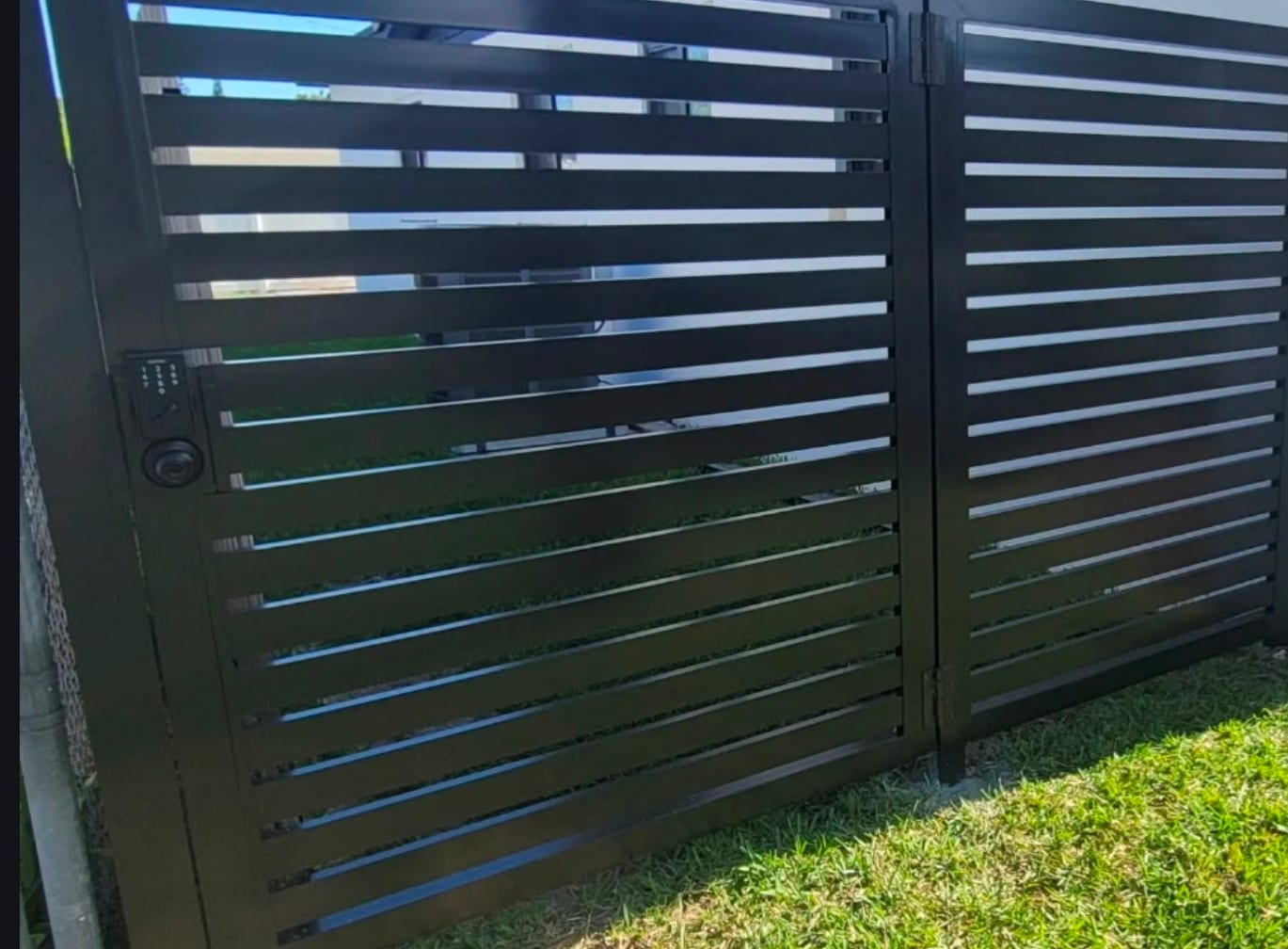 Horizontal-rail aluminum fence with open gaps along a residential lawn